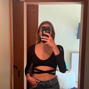 Black long sleeve crop top with a cross in the front, ties in the back.